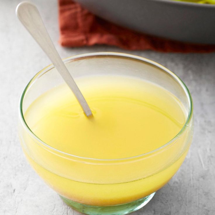 a glass bowl filled with yellow liquid and a spoon