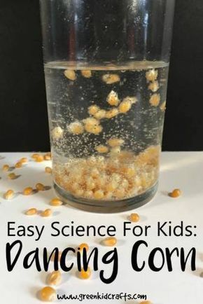 a glass filled with food sitting on top of a white table next to corn kernels