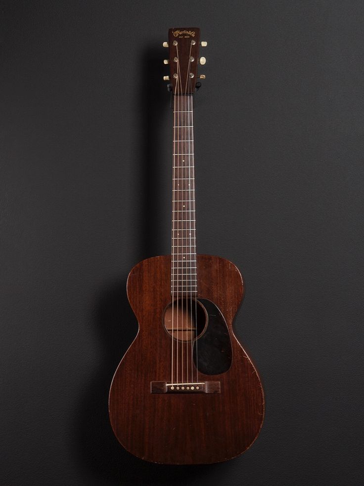 an acoustic guitar is hanging on the wall in front of a black background with copy space