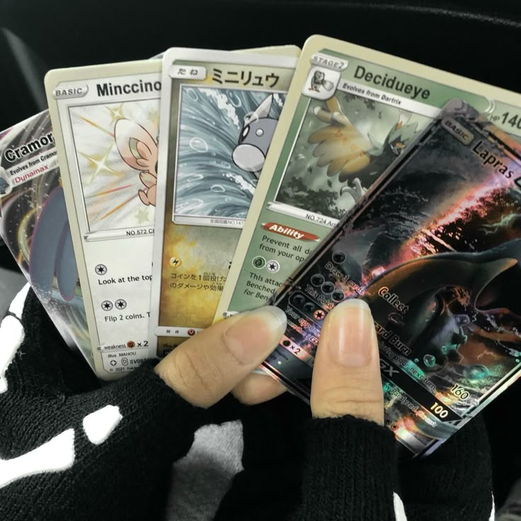 a person holding five different pokemon cards in their hands