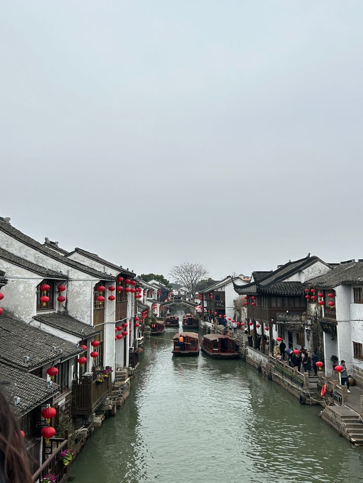 a river running through a village with lots of buildings on both sides and red lanterns hanging from the roof