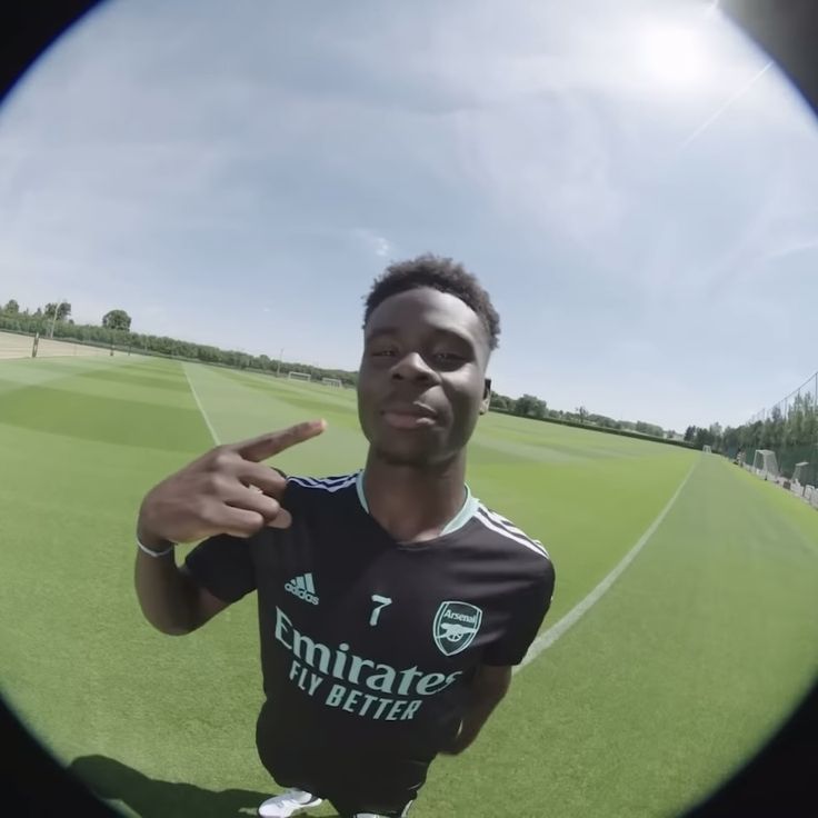 a young man in a soccer uniform pointing at the camera