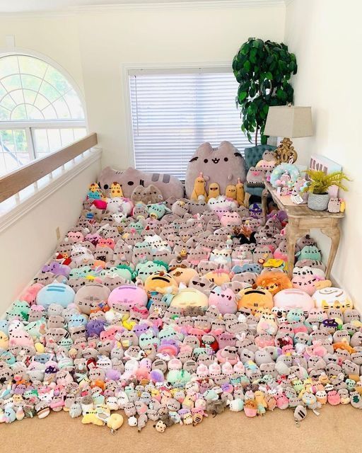 a pile of stuffed animals sitting on top of a carpeted floor next to a window