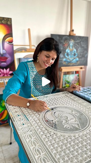 a woman sitting at a table working on an art project