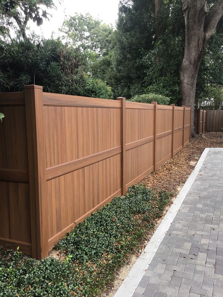 a wooden fence next to a brick walkway