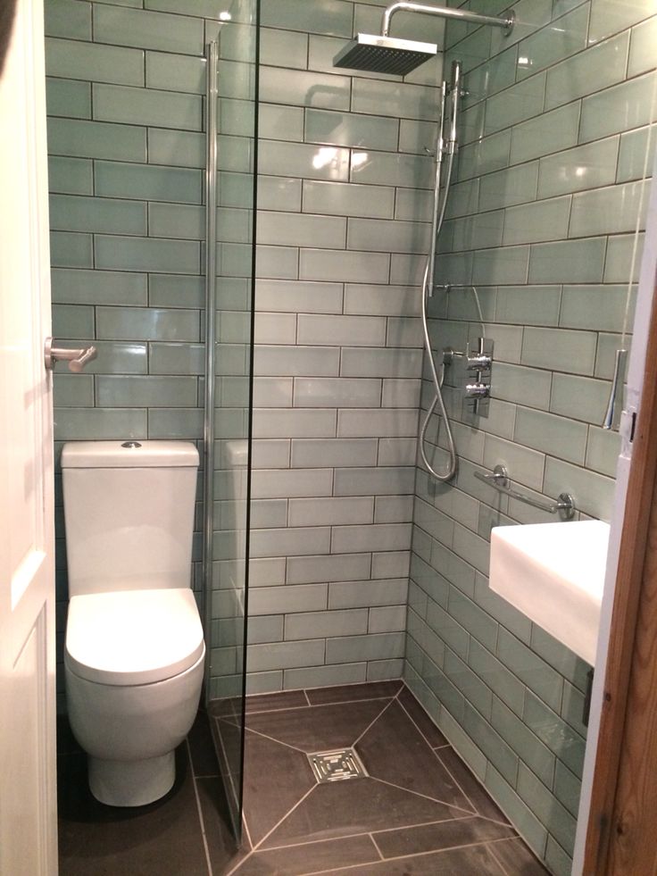 a bathroom with a toilet, sink and glass shower stall in the middle of it