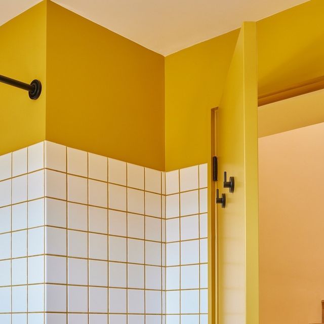 a bathroom with yellow walls and white tiles on the wall, along with a black door