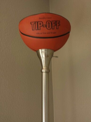 an orange basketball sitting on top of a metal pole in front of a white wall