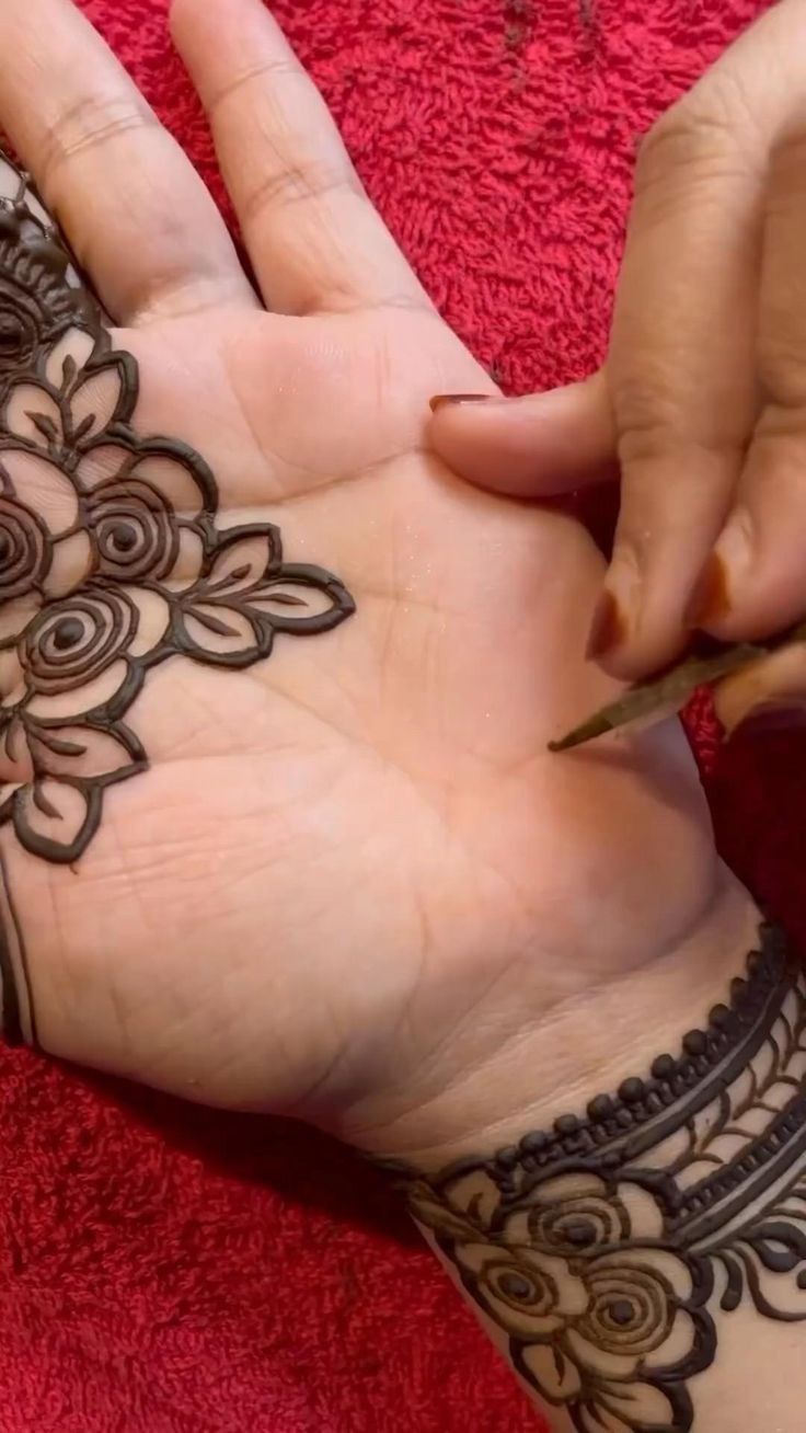 a woman is doing henna on her hand