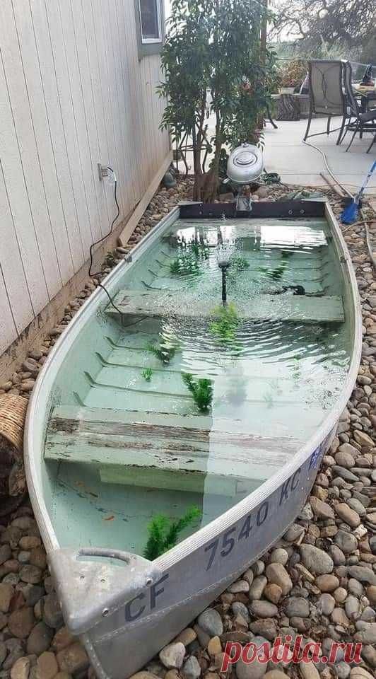 a small boat sitting on top of a pebble covered ground next to a building