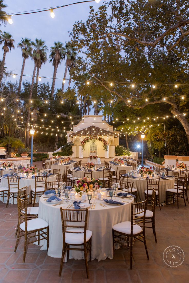 an outdoor dining area with tables and chairs set up for a formal function at dusk