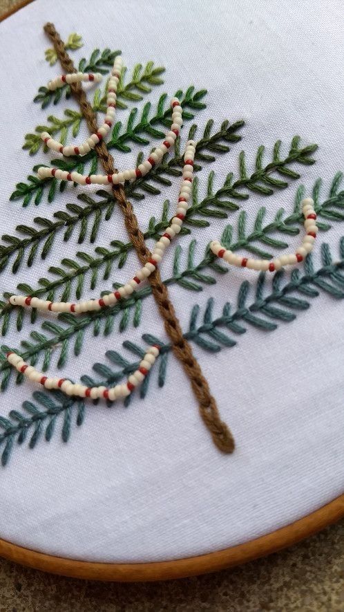 a close up of a embroidery on a piece of cloth with a tree in the middle