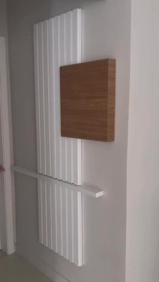 a white radiator mounted to the side of a wall next to a wooden shelf