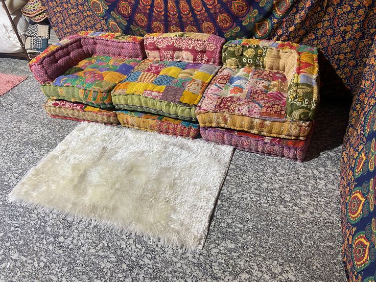 a multicolored couch sitting on top of a rug next to a white rug