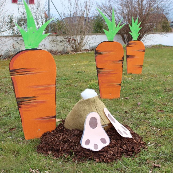 carrots are growing out of the ground with forks sticking out of them, in front of some grass