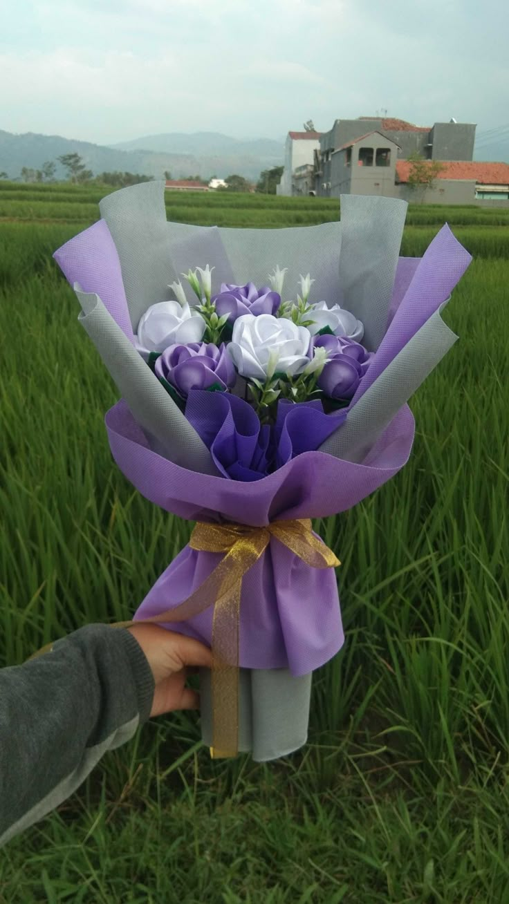 someone is holding a bouquet of flowers in the grass