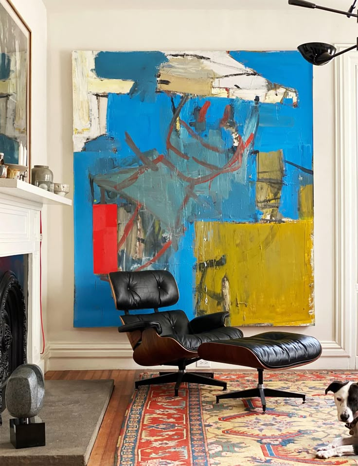 a living room with a large painting on the wall and a black chair in front of it