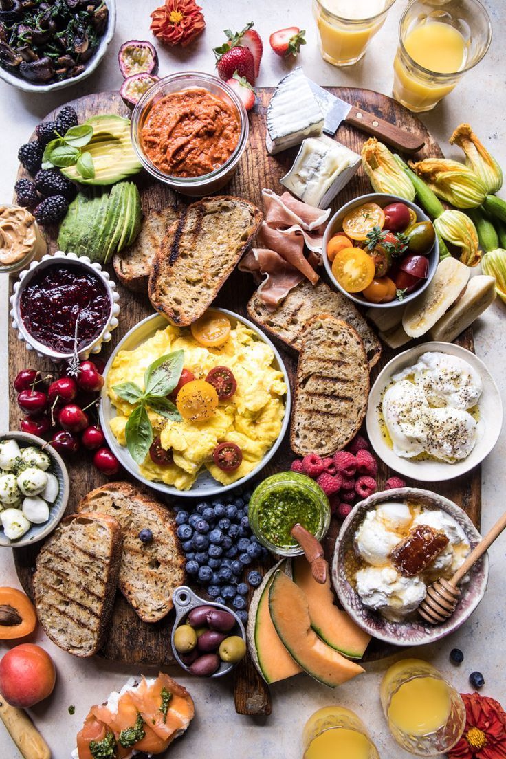 a table topped with lots of different types of food next to glasses of orange juice