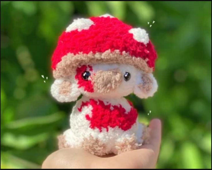 a small stuffed animal wearing a red and white knitted hat on it's hand