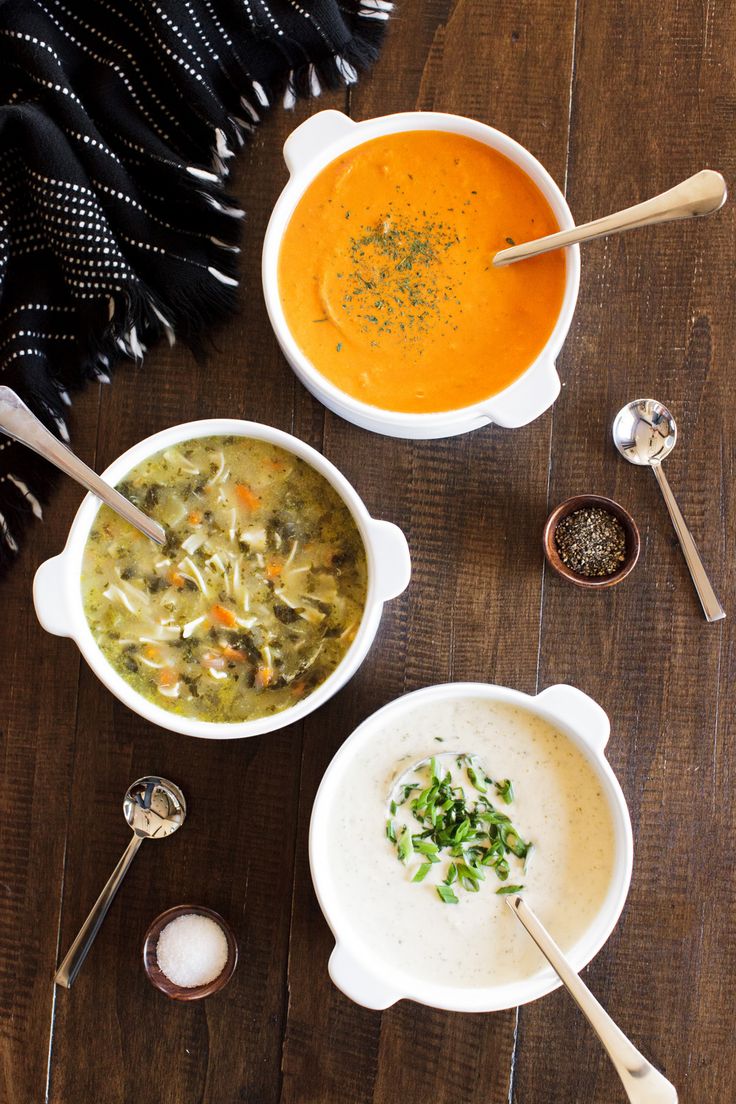 three bowls of soup on a wooden table