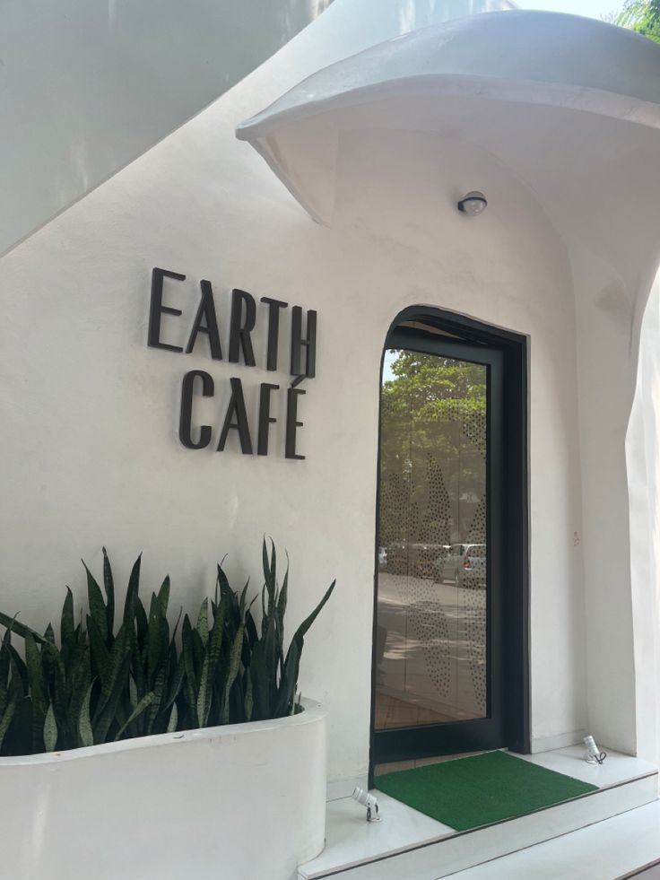 the entrance to earth cafe with potted plants