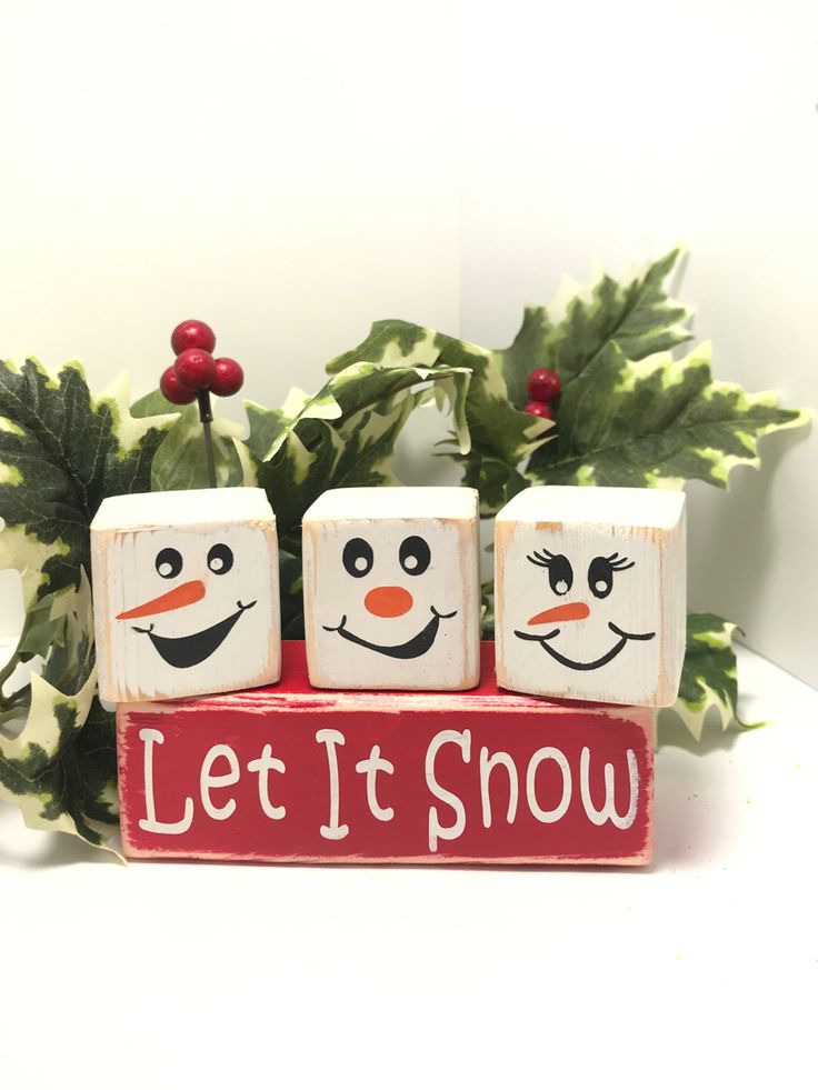 two snowman blocks with let it snow written on them and holly leaves in the background