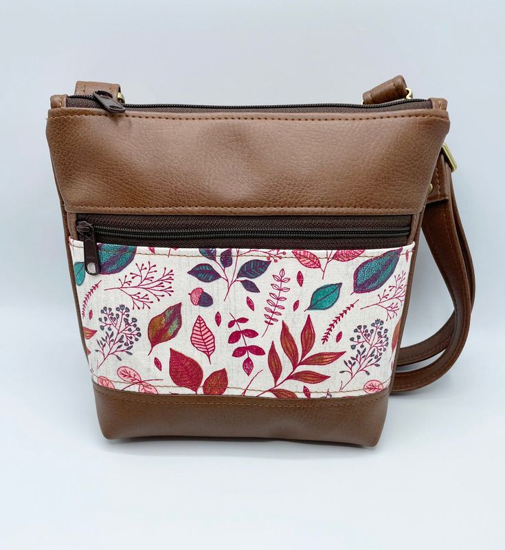 "Handcrafted small crossbody bag featuring a pretty fall leaves focus fabric and trimmed in a soft brown vinyl. This bag features a fully adjustable crossbody strap so you can wear over the shoulder or crossbody. Bag also has a waterproof canvas lining and front zippered pocket. Finished off with antique bronze hardware. This listing is for the bag ONLY. Matching accessories are available in the \"Accessories\" section of my shop. 8.5 Inches Tall 8.5 Inches Wide (across bottom) 2 Inches deep Fro Crossbody Bag Pattern, Vinyl Bag, Small Crossbody Purse, Bronze Hardware, Christmas Gift For Her, Soft Brown, Matching Accessories, Small Crossbody Bag, Small Crossbody