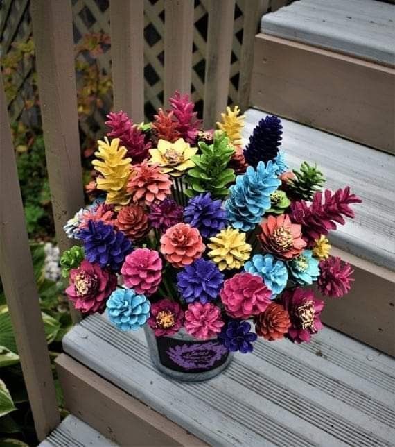 a vase filled with colorful flowers sitting on top of a wooden porch bench next to steps