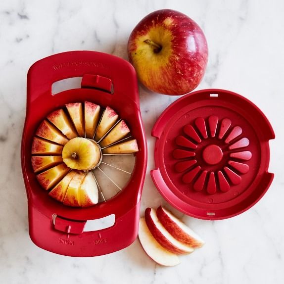 an apple slicer next to sliced apples on a marble counter top with the peeler removed