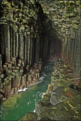 the inside of a cave with green water and rocks on either side, looking down at it