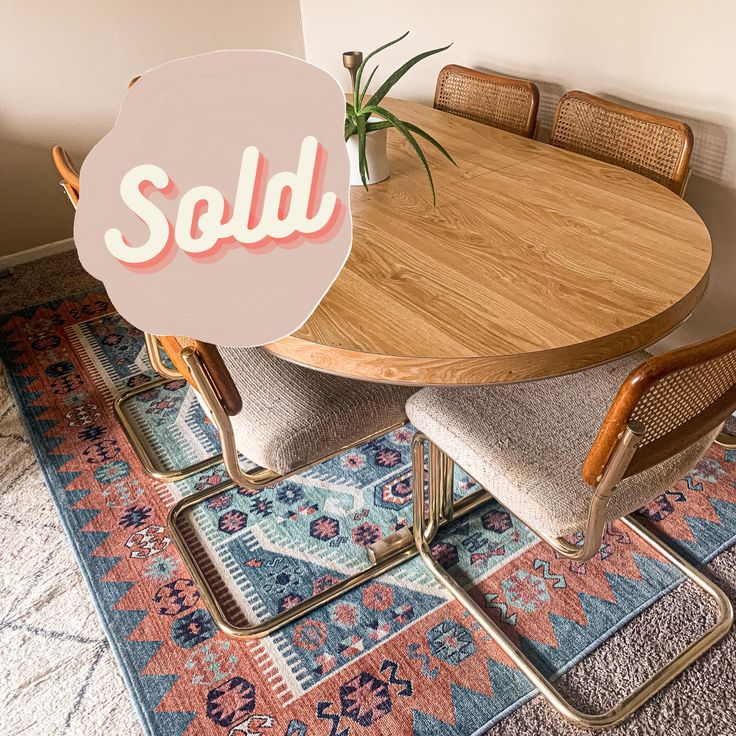 a wooden table with chairs and a sold sign on it's backrests