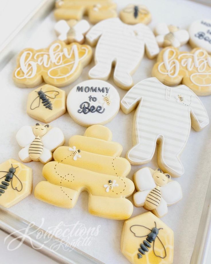 decorated cookies in the shape of baby's and honeybees on a tray