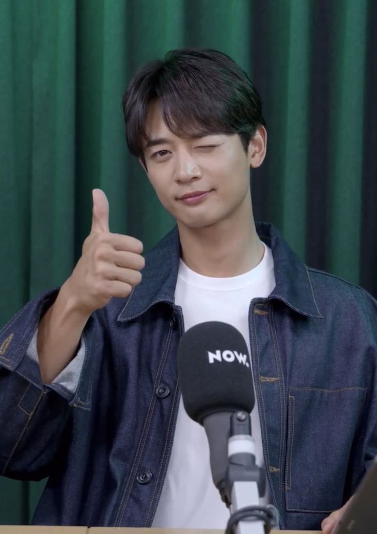 a man giving a thumbs up in front of a microphone