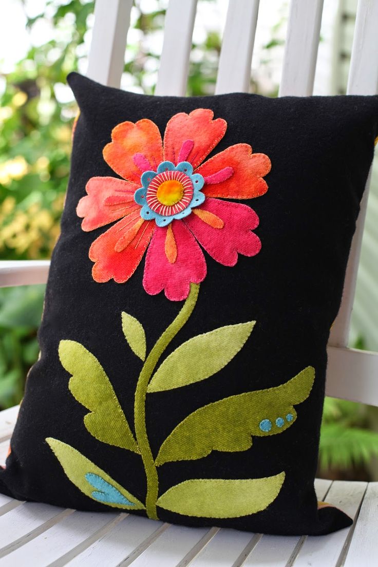 a black pillow with an orange flower on it