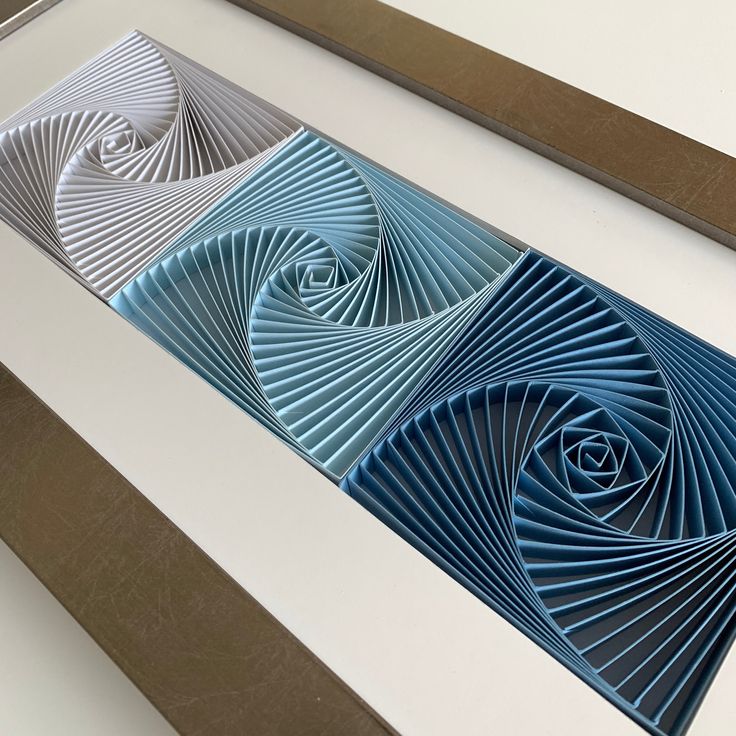 three blue and white paper art pieces sitting on top of a table