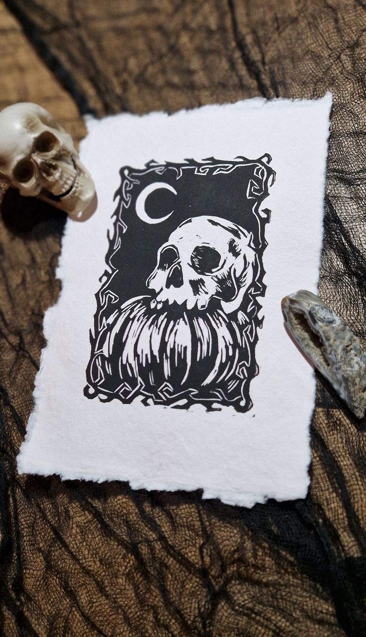 a piece of paper with a skull on it next to some rocks and a small object