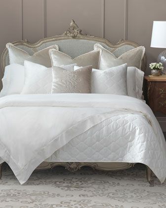 a bed with white comforters and pillows on it