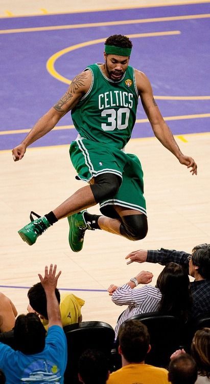 a basketball player is jumping in the air with his feet on the court while people watch