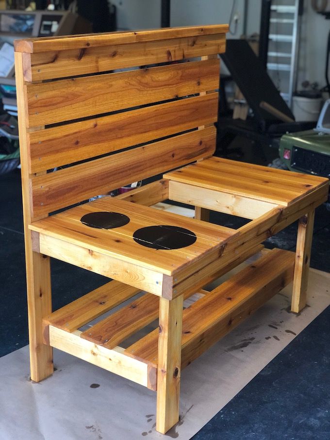 a wooden bench sitting on top of a hard wood floor next to a metal object