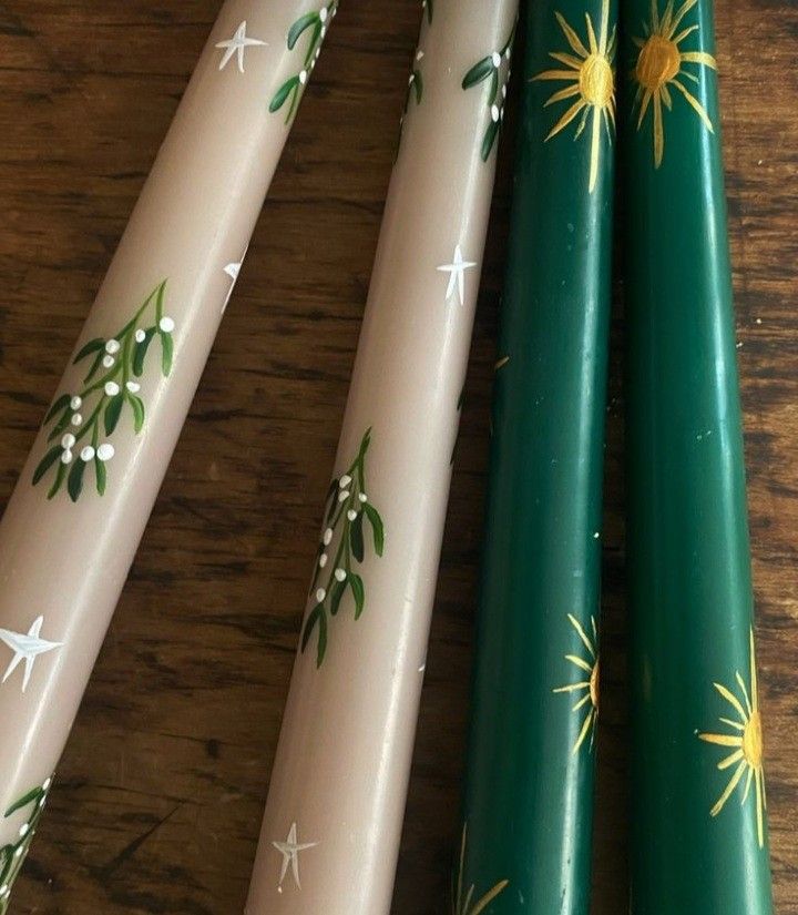 three green and white christmas candles sitting on top of a wooden table next to each other