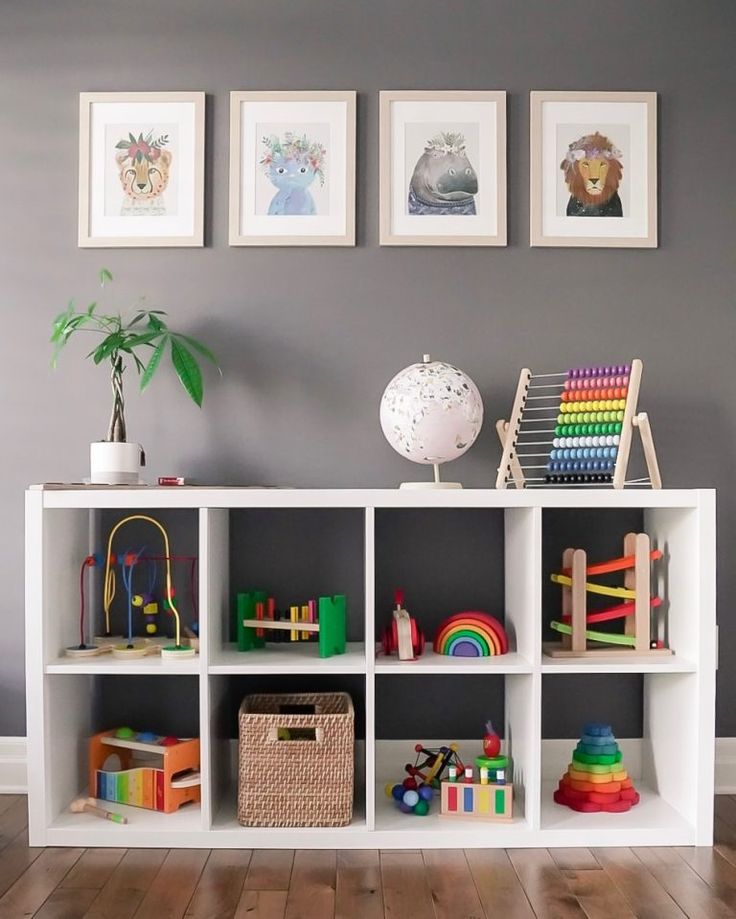 a white book shelf filled with lots of toys next to two pictures on the wall