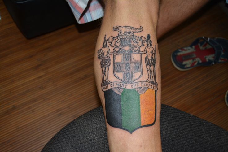 a man's arm with a flag and coat of arms tattoo on the wrist