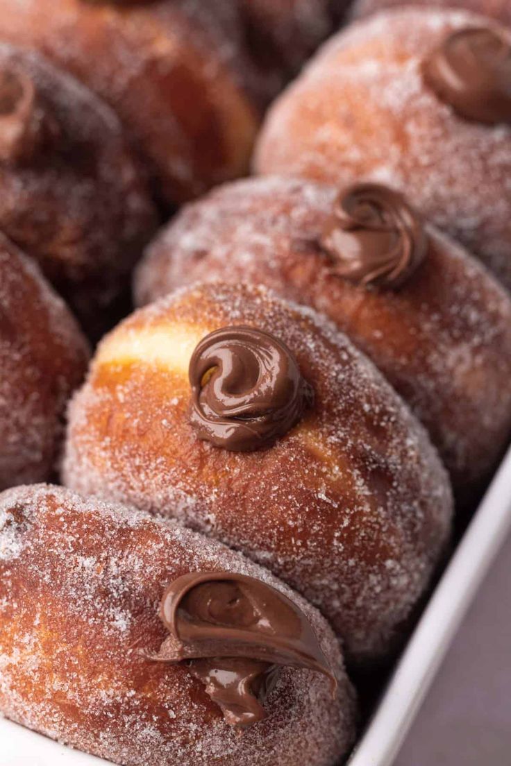 chocolate filled donuts in a white box with powdered sugar on the top and bottom