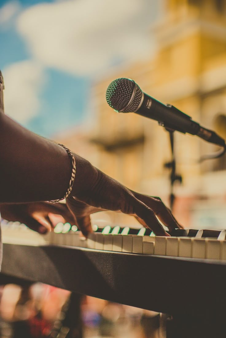 a close up of a person's hand on a keyboard with a microphone in the background