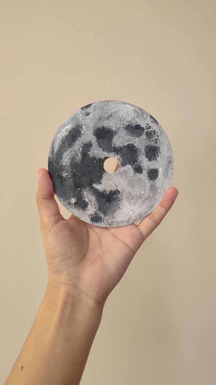 a person holding up a doughnut with the moon on it's side in their hand