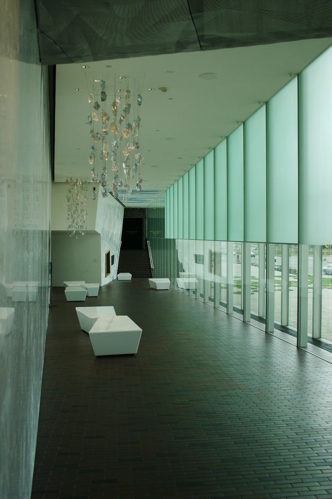 an empty room with glass walls and chandelier hanging from the ceiling in front of it