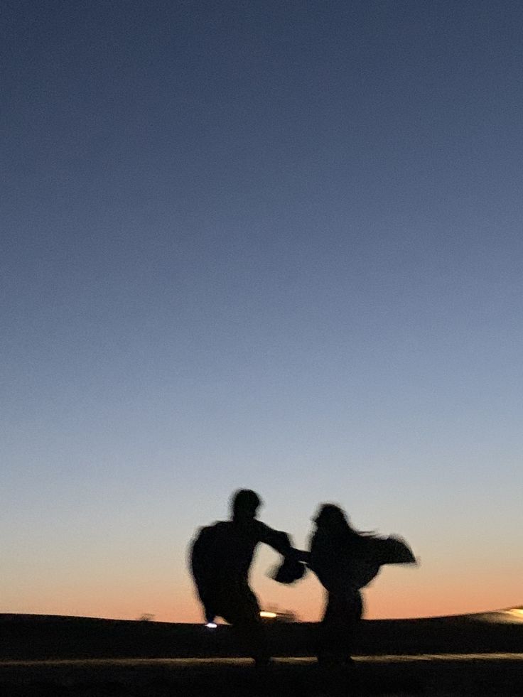 two people are silhouetted against the evening sky with their arms in each other's pockets