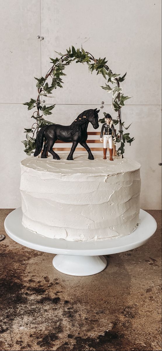 a white cake topped with a horse figurine on top of a wooden table