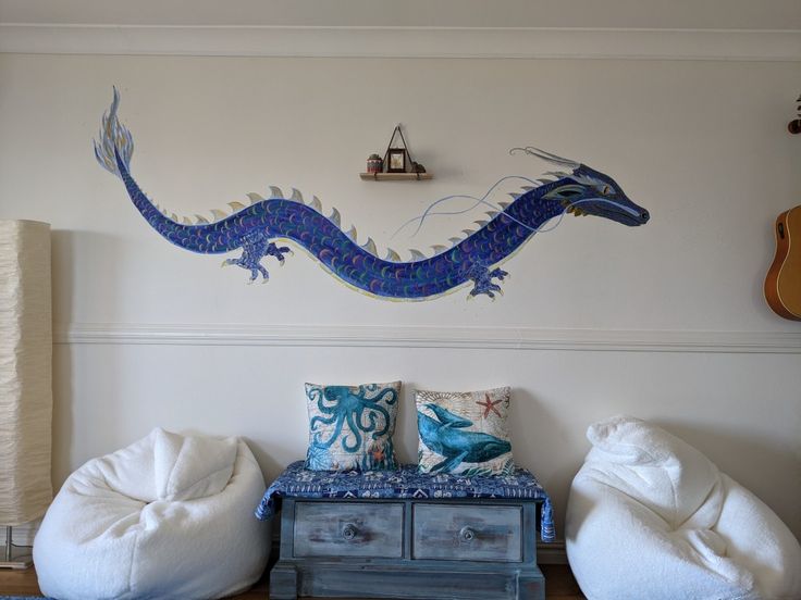 a living room with two bean bags on the floor and a blue dragon painted on the wall