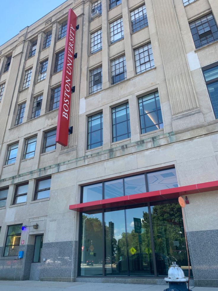 a tall building with many windows and a red sign on it's front door